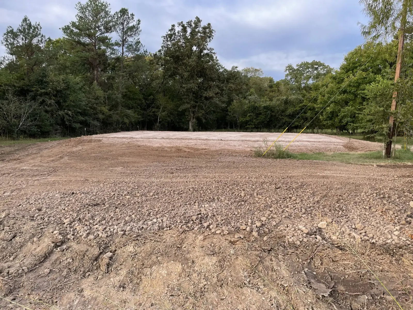 Newly built house pad on cleared raw land edged by trees