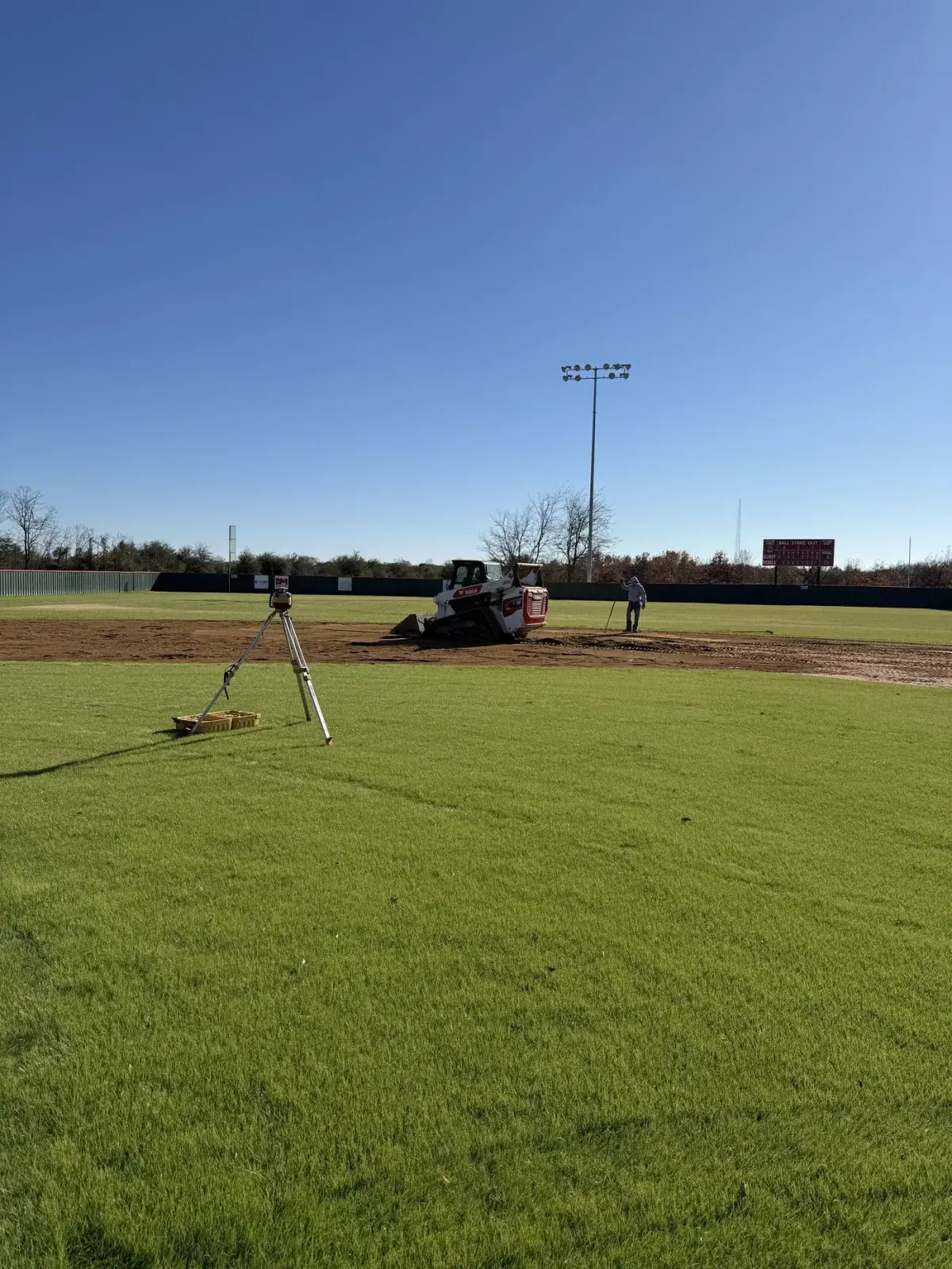 Baseball infield being graded with a laser level and track loader