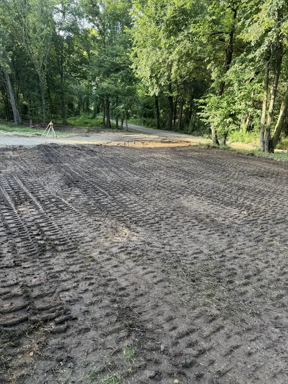 Graded building pad on a wooded homesite with a laser level set up