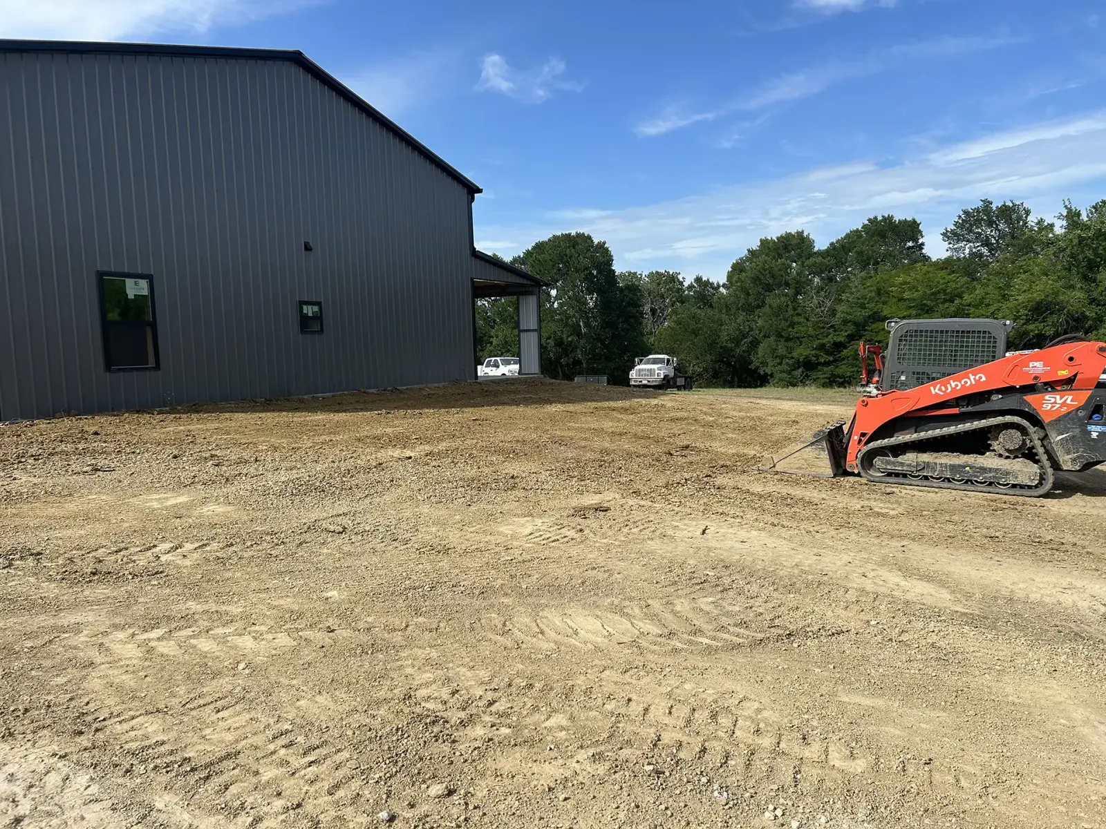 Graded pad beside a new metal shop building with a track loader