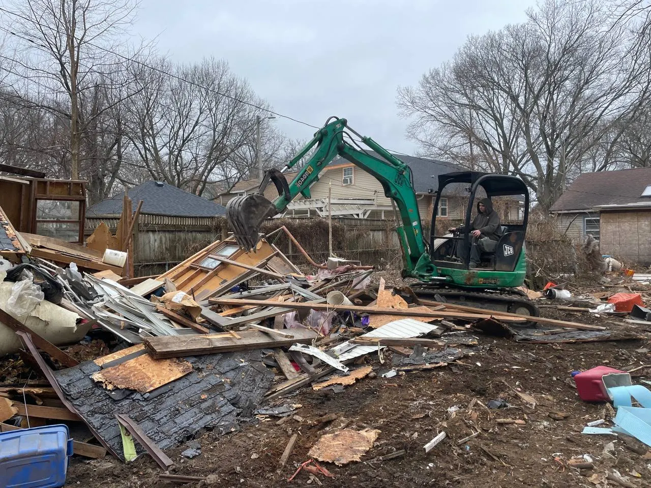 JCB excavator working through demolition debris from a house tear-down