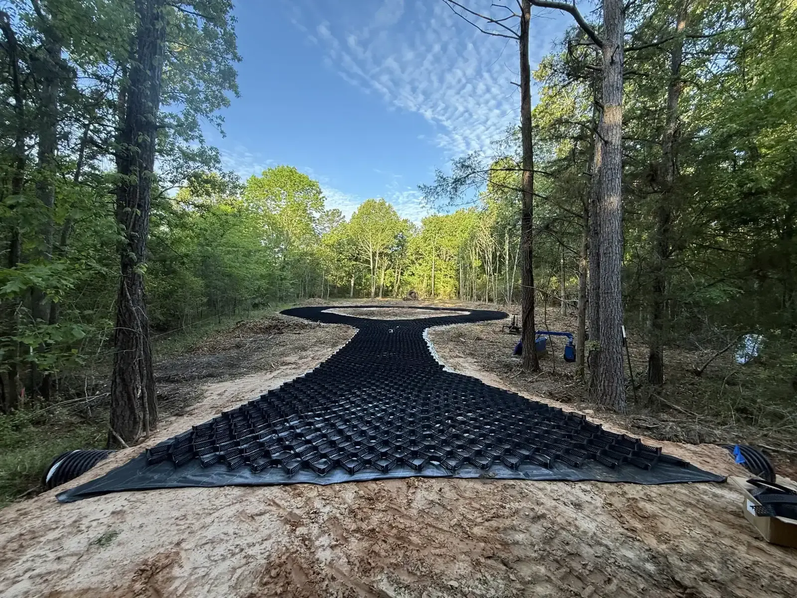 Geogrid laid out on a graded path to stabilize a new driveway base