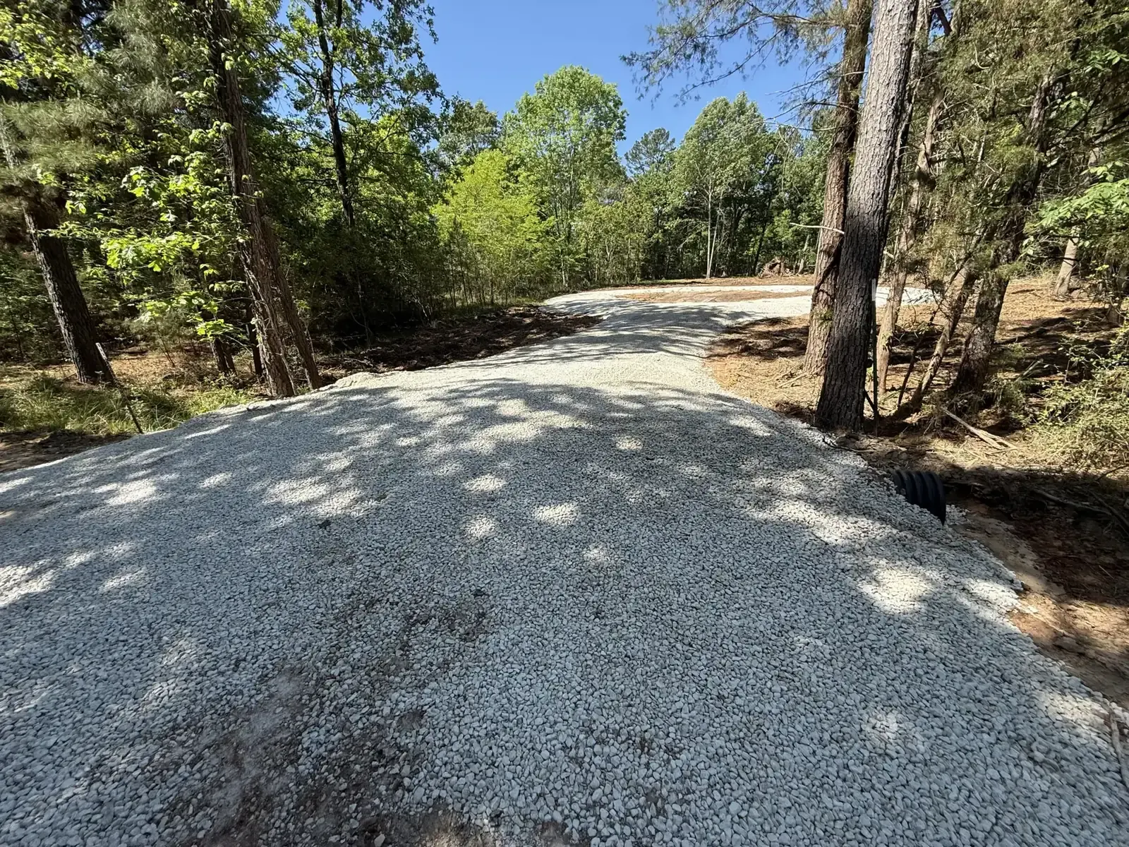 Newly built gravel driveway curving through a wooded lot