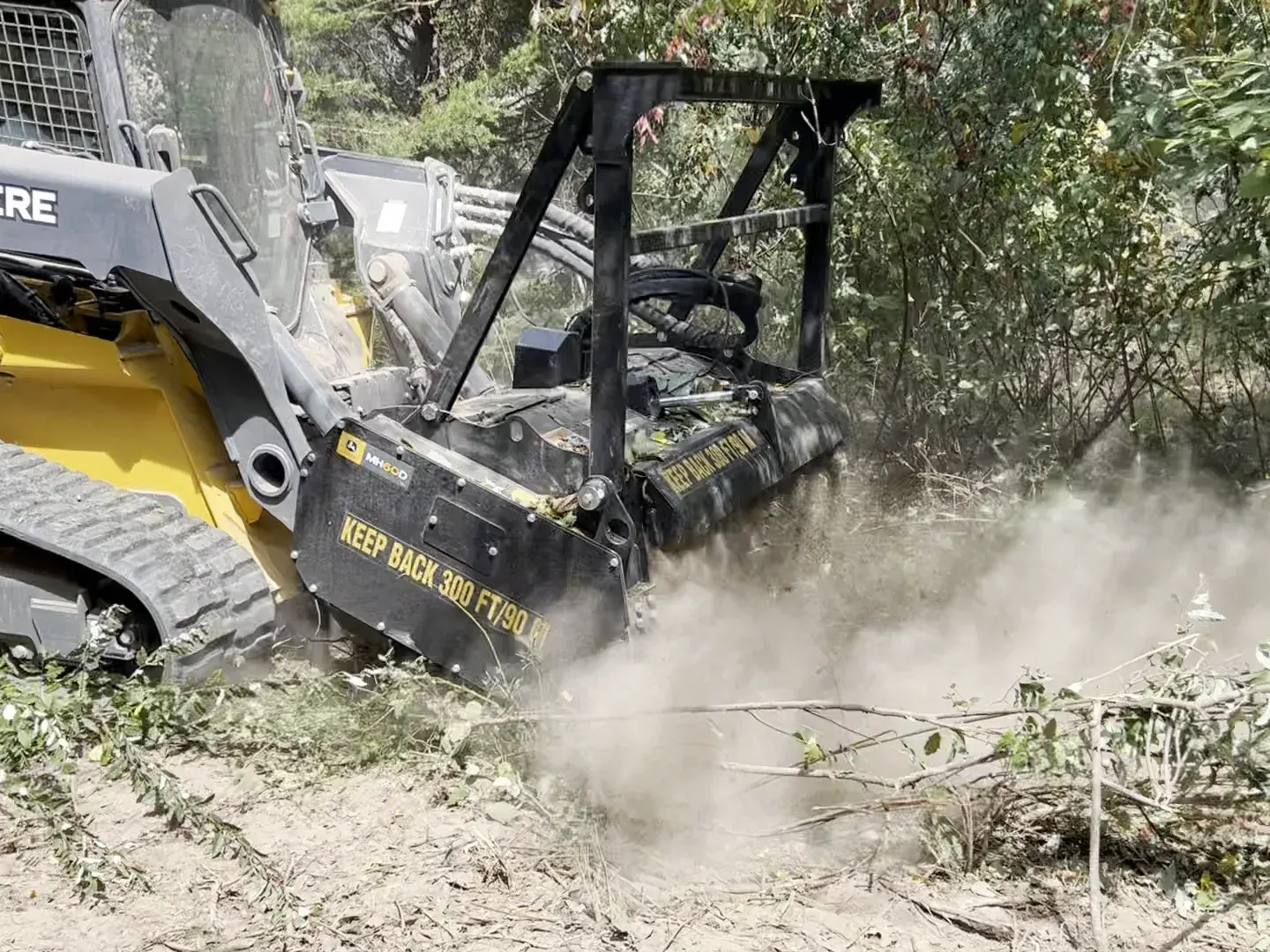 Mulching head grinding saplings and brush with dust in the air