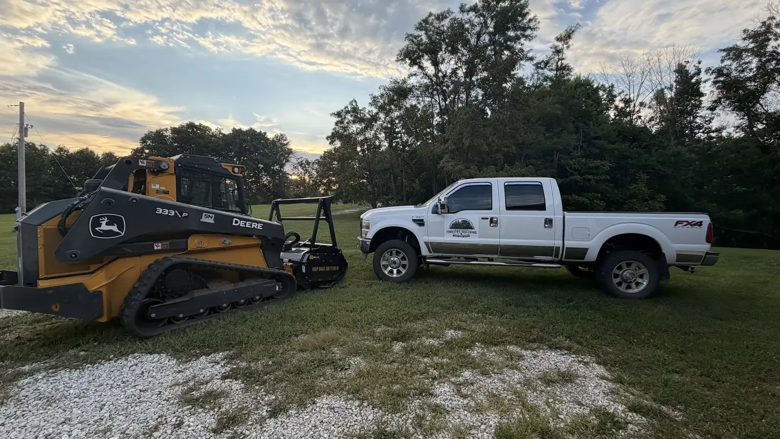 Company truck parked beside the forestry mulcher at sunset