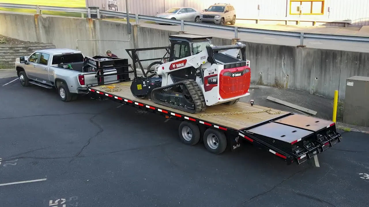 Bobcat track loader with mulcher loaded on a trailer behind a pickup