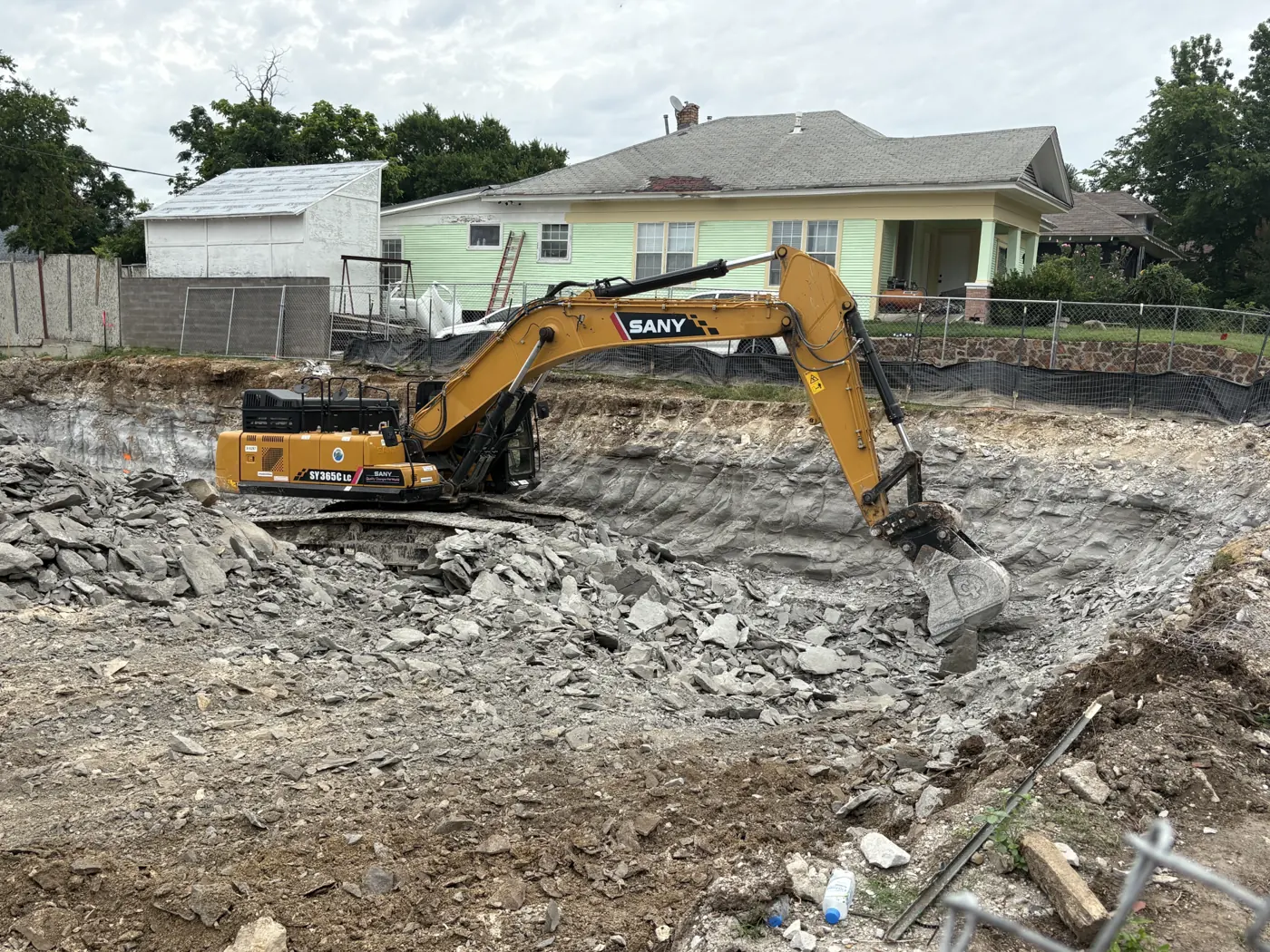 Excavator breaking out a demolished house on a Granbury lot
