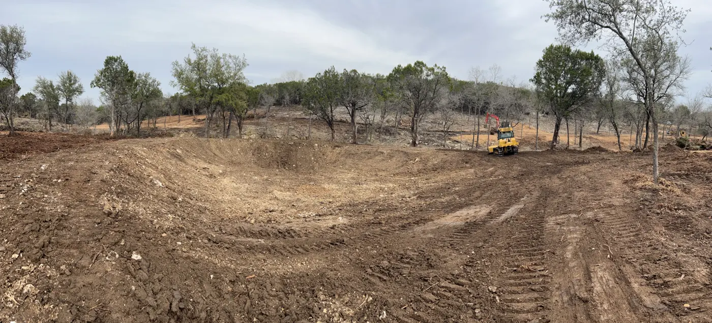 Cleared wooded acreage with equipment working in the background, Central Texas