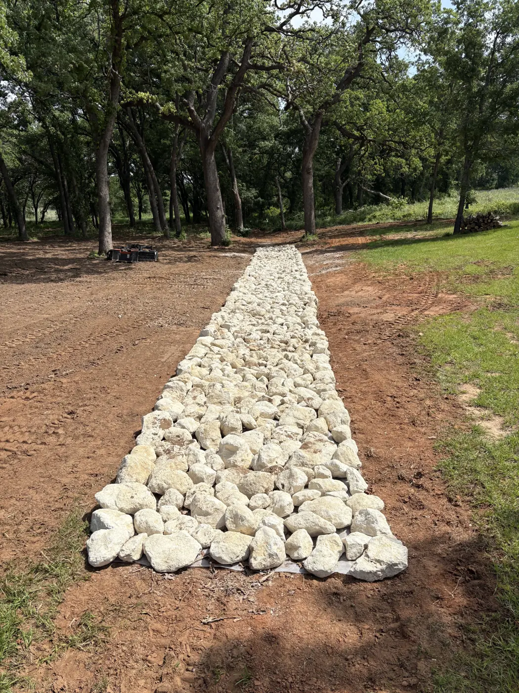 Rock-lined drainage swale built through a wooded lot in Central Texas