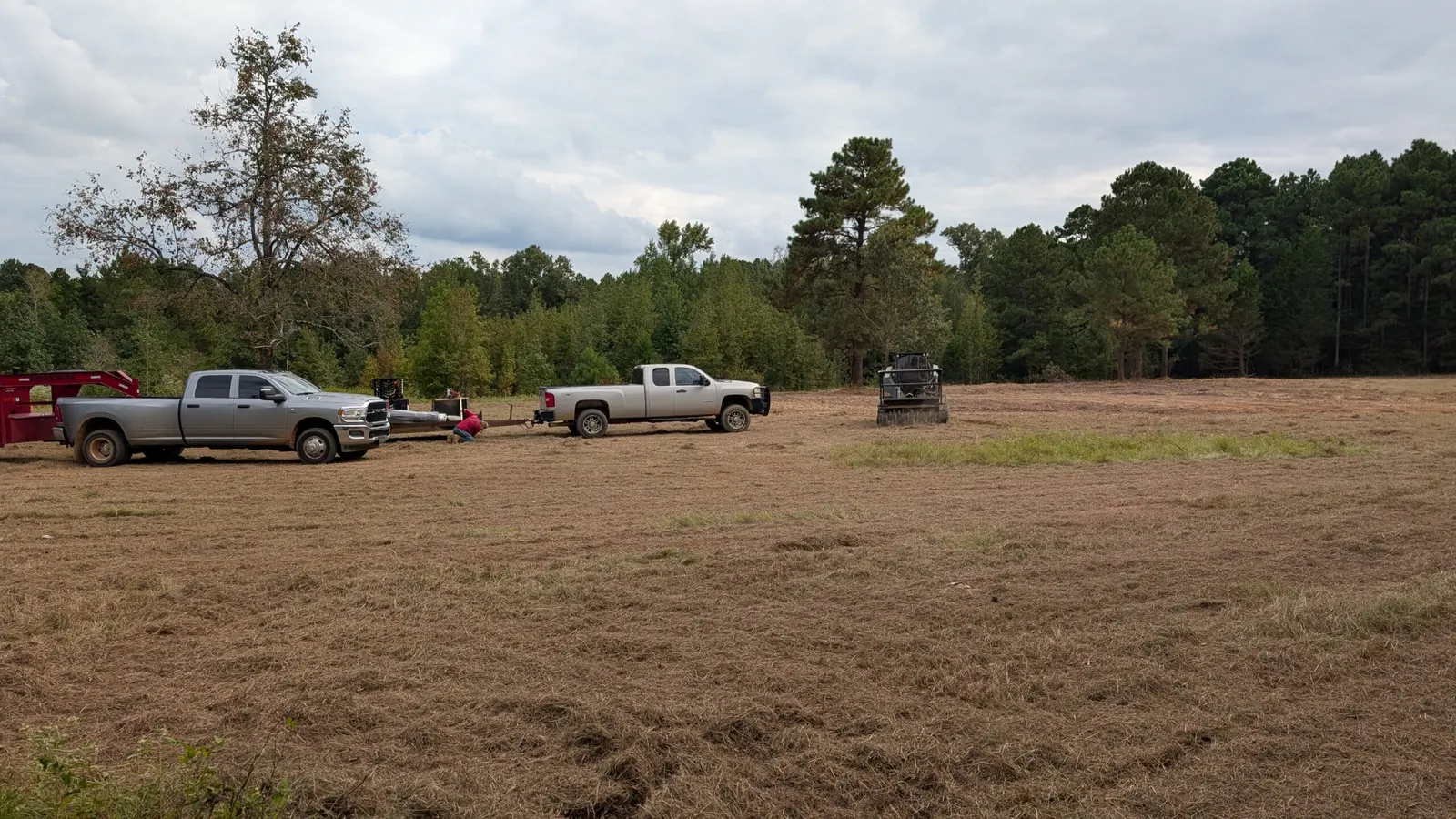 Large tract of cleared acreage with work trucks and a track loader in Northeast Texas