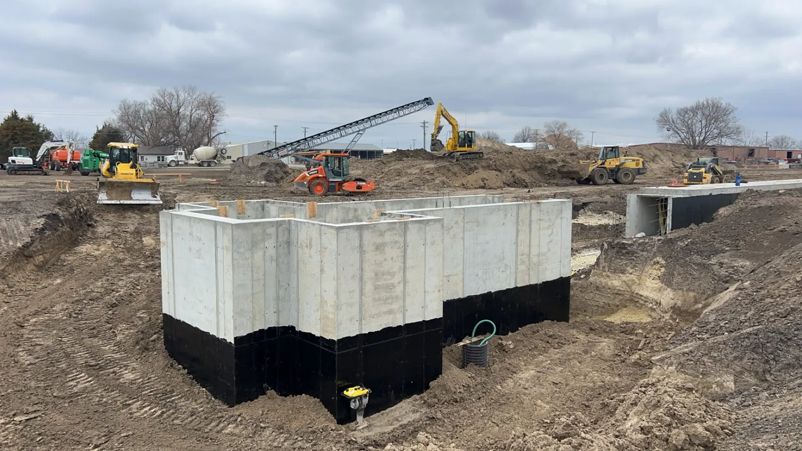 Concrete foundation in an excavated site with equipment working around it in north-central Kansas