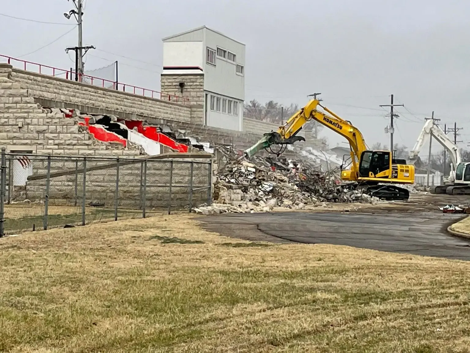 Excavator demolishing a concrete grandstand structure