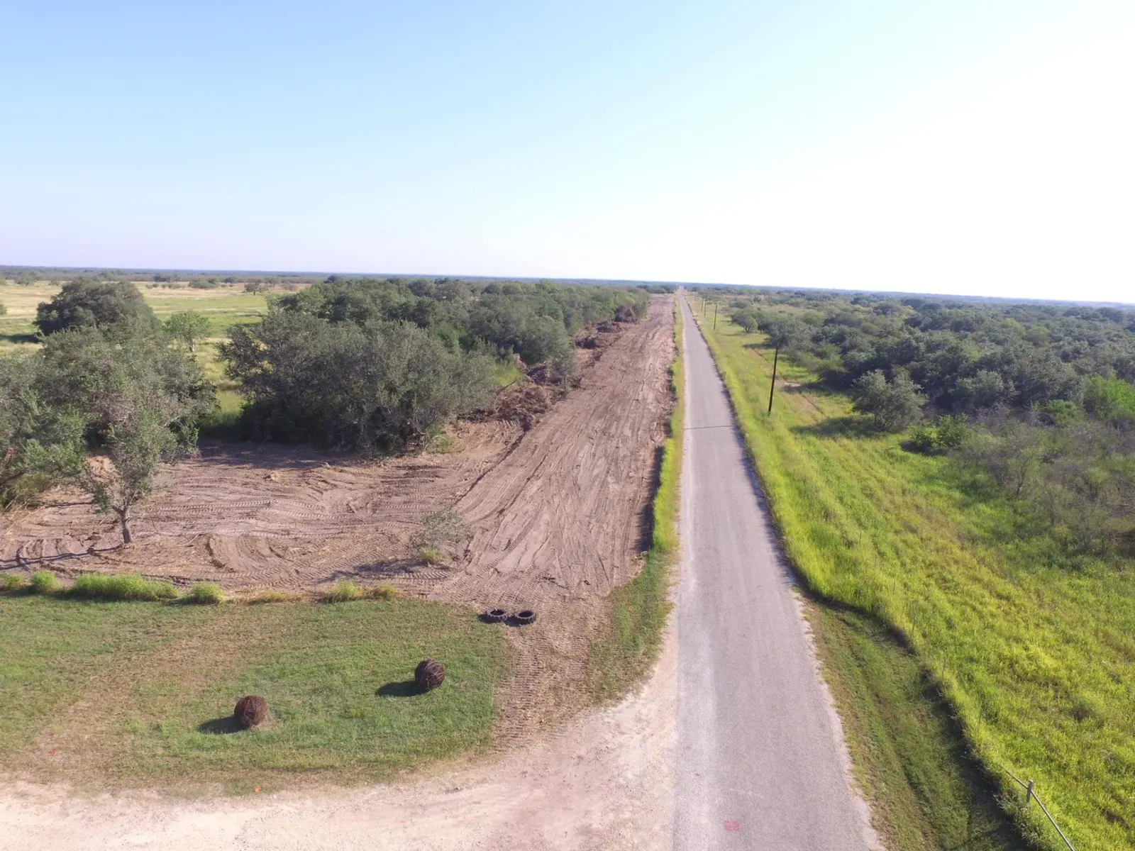 Aerial view of a cleared fence line running beside a rural road