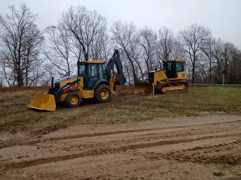 John Deere backhoe and dozer on a cleared Tennessee property