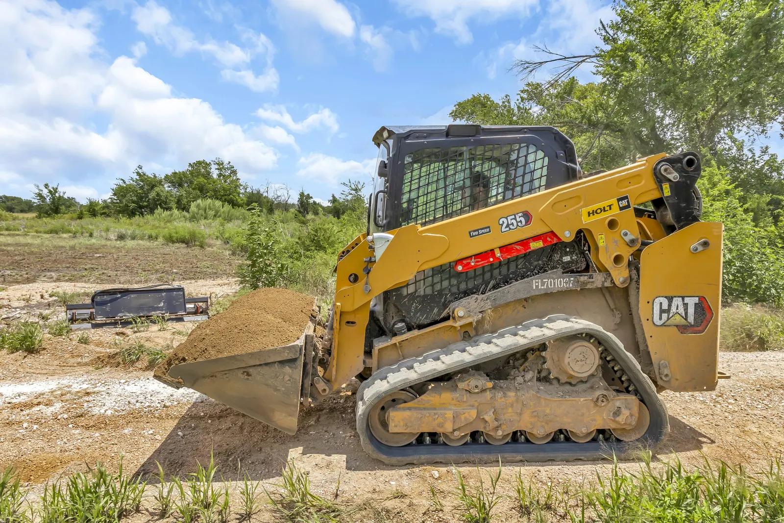 CAT compact track loader with bucket on a dirt work site