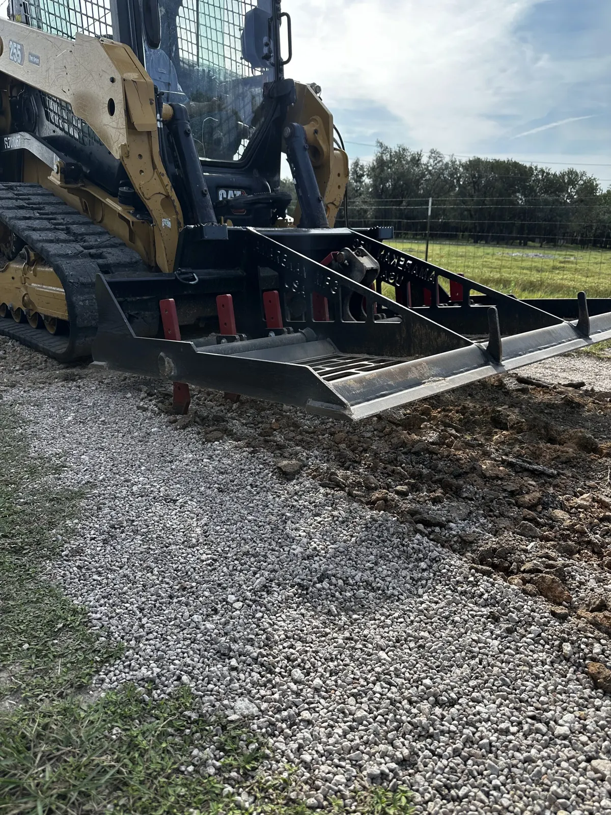 Skid steer with leveling attachment smoothing a gravel driveway in Central Texas