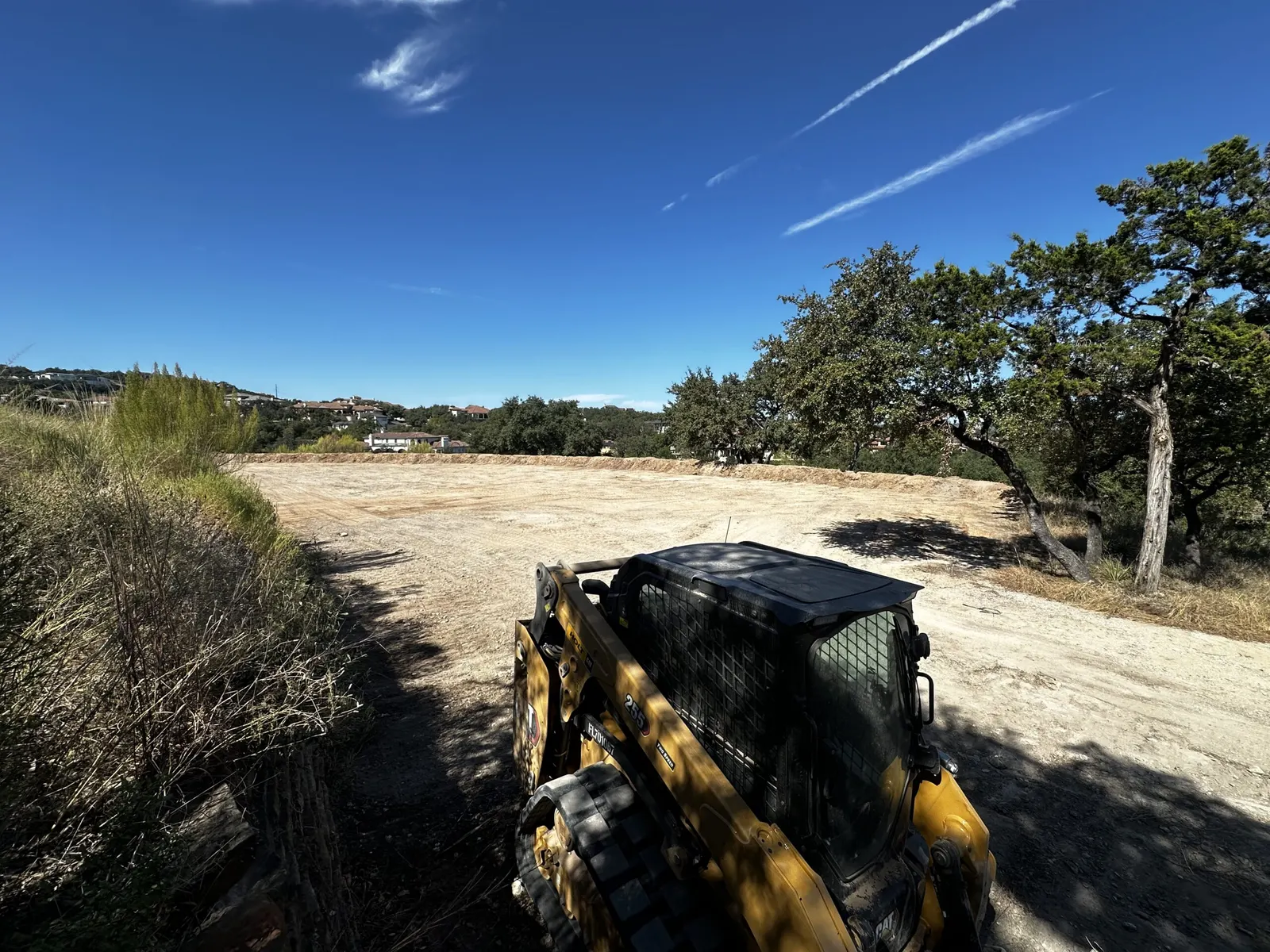 Track loader on a large cleared and leveled pad in the Hill Country