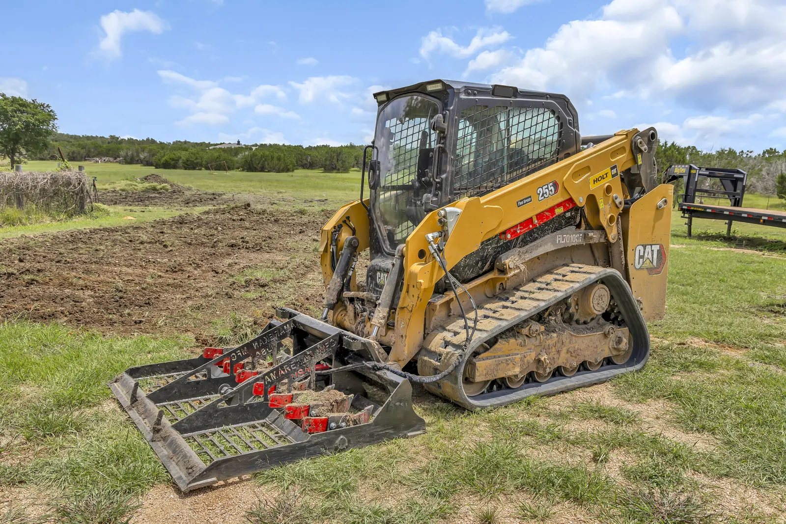 Track loader with a rock rake attachment leveling ground