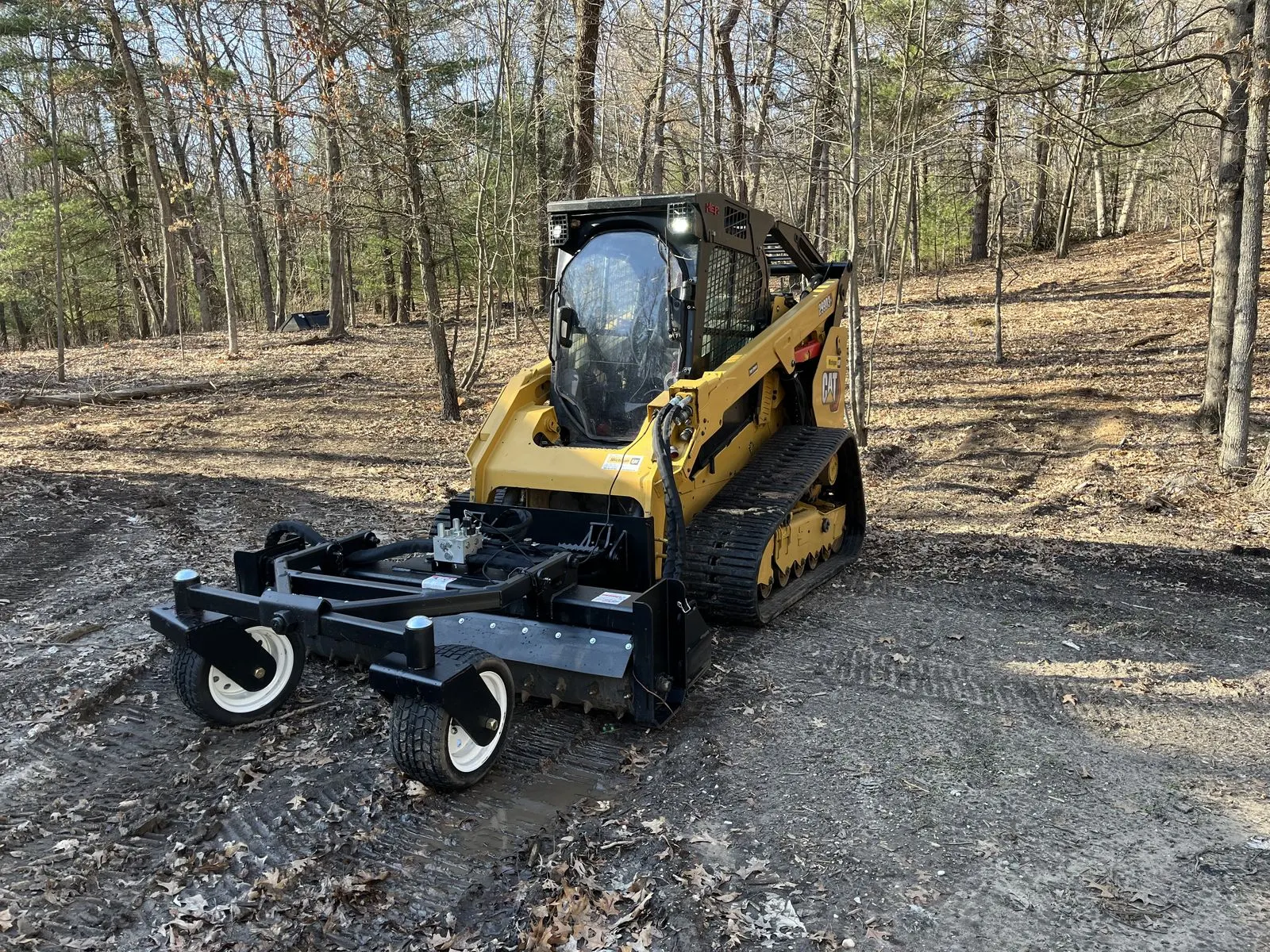 Compact track loader fitted with a power rake attachment