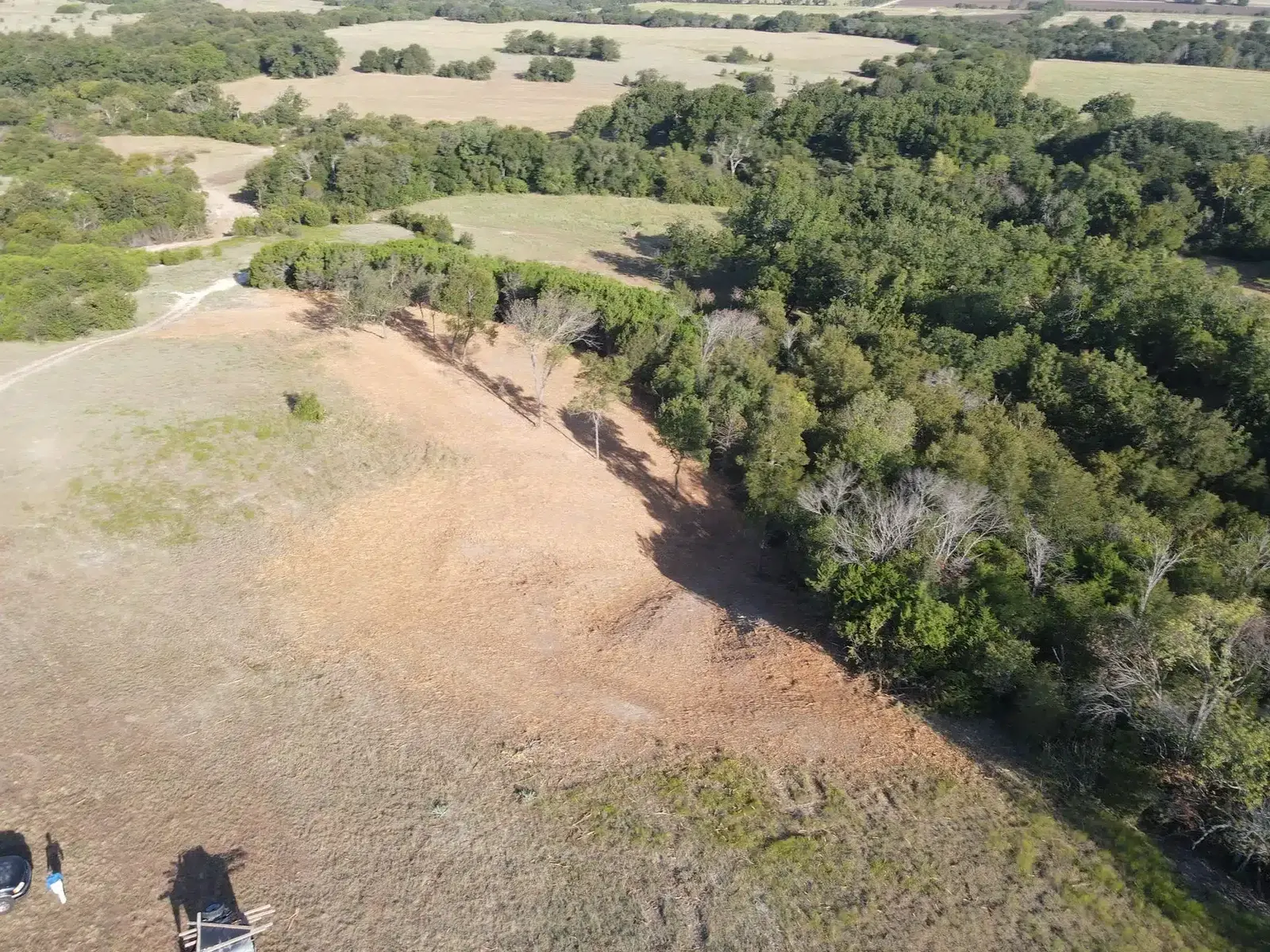 Drone view of a cleared hillside strip next to wooded land in Central Texas